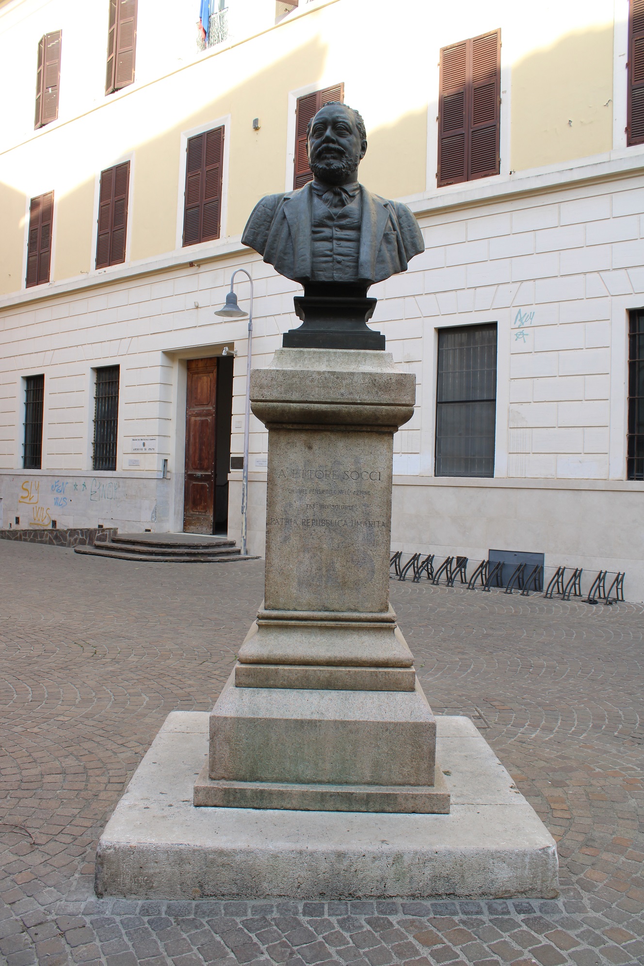 Statua di Ettore Socci, dal quale prende il nome la piazza dove ha sede l'Archivio di Stato di Grosseto, sullo sfondo l'ingresso all'Archivio.